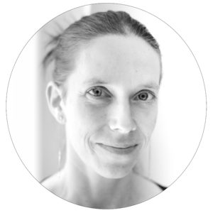 Portrait d'Isabelle, en noir et blanc. Elle a la peau blanche, les cheveux lisses châtains attachés en chignon. Elle sourit doucement en regardant la caméra.