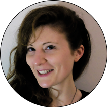 Portrait d'Éline, en couleur. Elle a la peau blanche et les cheveux chatains, longs et épais, ondulés. Elle regarde l'objectif en souriant.