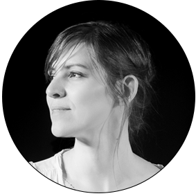 Photo en noir et blanc. Le visage de profil, Marie-Hélène Bellavance, devant un fond noir avec un léger sourire.